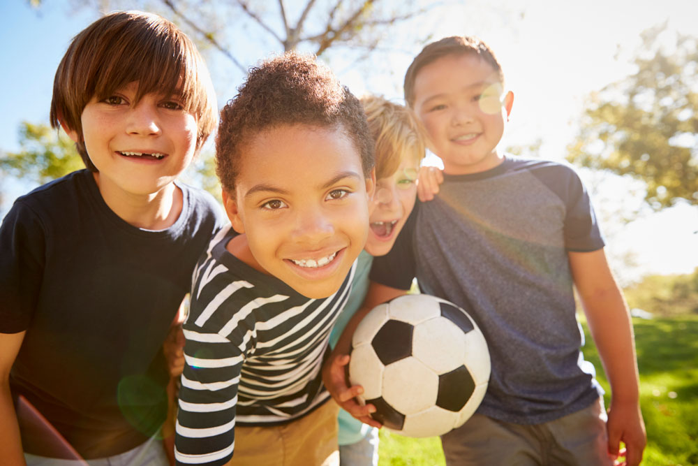 Boys smiling holding a soccer ball