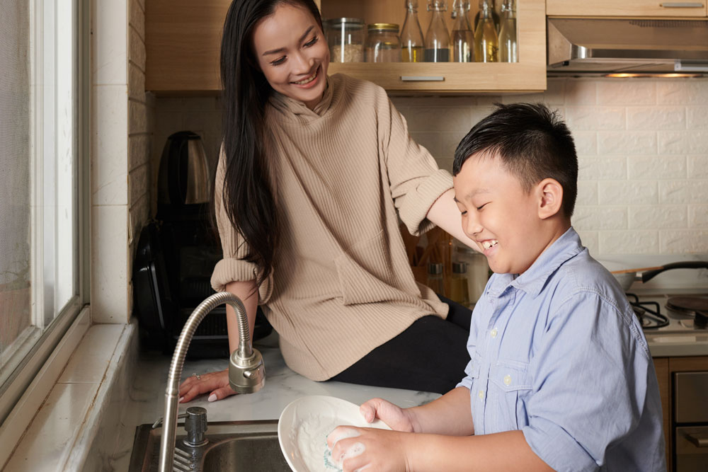 Smiling boy washing dishes